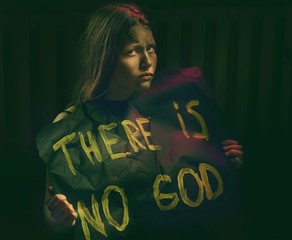 Teen girl with dirty face holding banner with a text .Atheist 