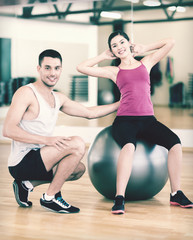 Obraz premium male trainer with woman doing crunches on the ball