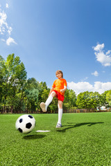 Naklejka premium Boy kicking football with one leg