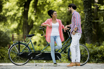 Young couple riding on the tandem bicycle