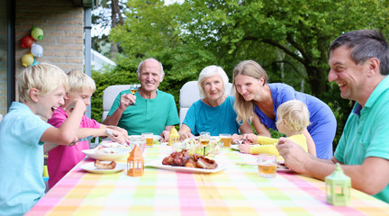Happy family with kids and grandparents having lunch together