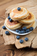 Pancakes with fresh blueberries over rustic wooden background