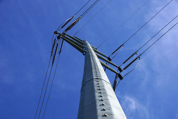 Fototapeta premium High Voltage Power Lines intersect at a large metal Utility pole