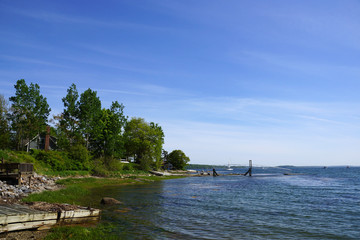 Fototapeta premium Rocky coastline with pier in distance and green trees