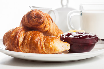 Fresh croissants with butter and a glass of milk