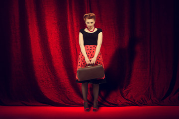 woman  is on the stage  on a background of red curtain.