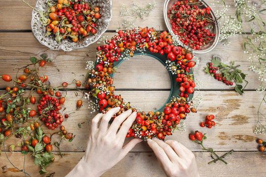 Florist at work: woman making rose hip and hawthorn wreath