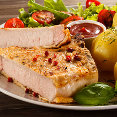 Fried pork chop, boiled potatoes and vegetable salad
