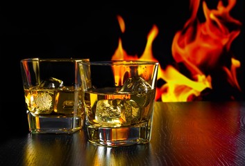 glasses of whiskey with ice cubes in front of the flame