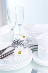 Set of white dishes on table on light background