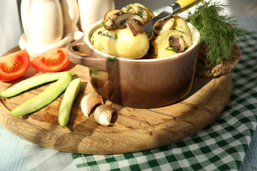Young boiled potatoes in pan with vegetables on table in