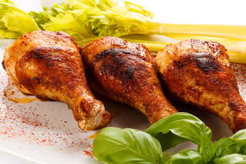 Grilled chicken legs and vegetables on white background