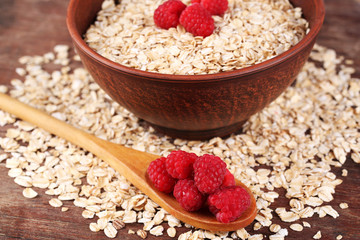 Big brown bowl with oatmeal and berries on a wooden table