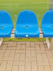 Detail of blue plastic seats on outdoor stadium players bench