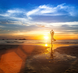 Silhouette of a beautiful yoga woman at sea sunset.