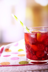 Glass of cold berry cocktail with lemon on wooden table