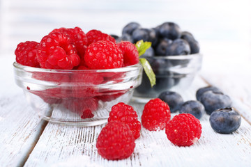 Glass bowls of raspberries and blueberries