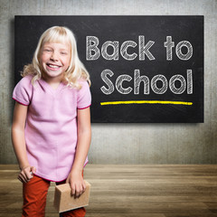 kid standing in front of a blackboard with text 'back to school'