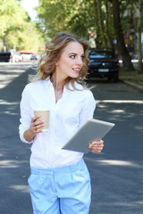 Beautiful young girl with tablet on city street