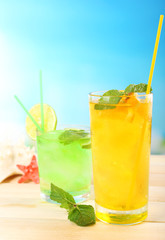 Refreshing cocktail on wooden table on blue background