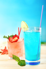 Refreshing cocktail on wooden table on blue background