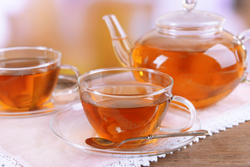 Teapot and cups of tea on table on light background
