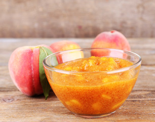 tasty peach jam with fresh peaches on wooden table
