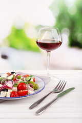 Greek salad served in plate with glass of wine