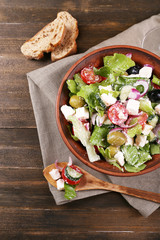 Greek salad served in bowl with slice of bread