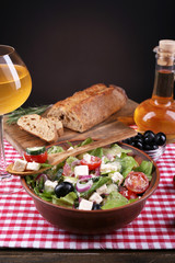 Bowl of Greek salad served with olive oil and glass of wine