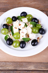 tasty salad with grape and cheese on wooden table
