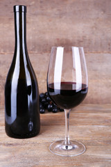 Tasty wine and ripe grape on wooden background