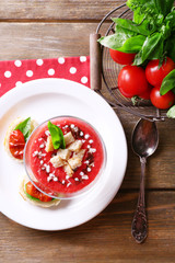 Gazpacho soup in glass bowl, on color wooden background
