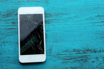 Modern mobile phone with broken screen on wooden background