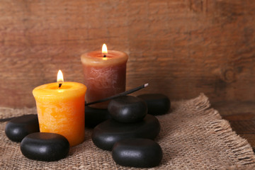 Spa stones with candles on wooden background