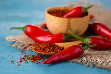Milled red chili pepper in bowl on wooden background