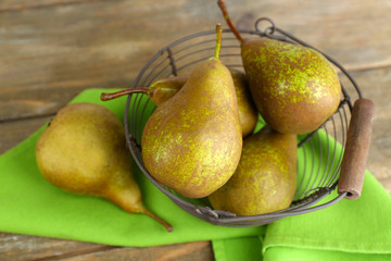 Ripe pears in basket, on wooden background