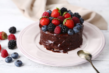 Tasty chocolate cake with different berries, on wooden table