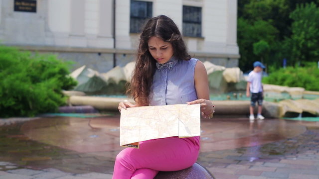Woman sitting on the stone and reading map