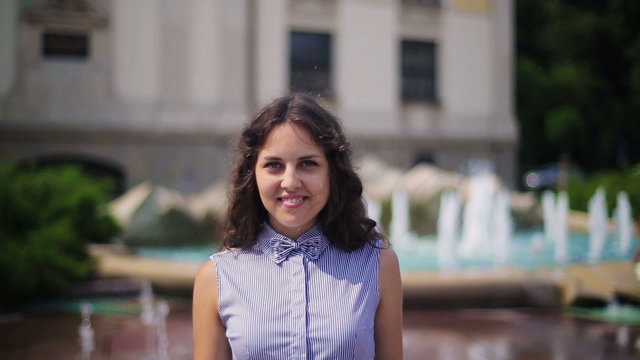 Woman smiling to the camera next to the fountain 