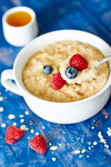 Porridge with berries and honey on a spoon