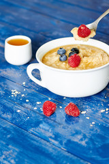 Porridge with berries and honey on table