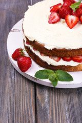 Delicious biscuit cake with strawberries on table close-up