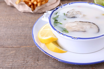 Tasty soup with oysters on wooden table