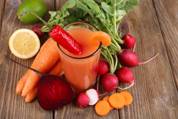 Fresh carrot juice with vegetables on wooden background