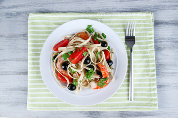 Fresh prawns with spaghetti, olives, tomatoes and parsley in a