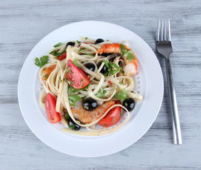 Fresh prawns with spaghetti, olives, tomatoes and parsley in a