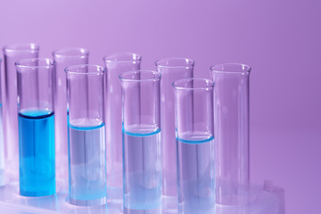 Test-tubes with blue liquid on purple background
