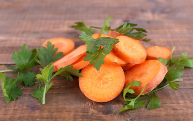 Slices of carrot and parsley on wooden background