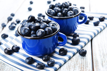 Delicious blueberries in cups on table close-up